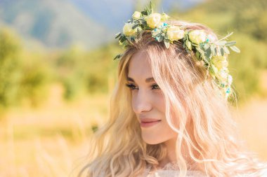 Alanında yaz aylarında bir çiçek çelenk ile boho tarzında beyaz bir elbise güzel genç kadın portre.