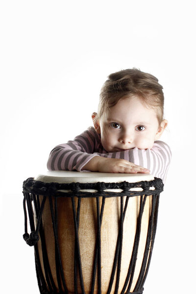 A portrait of cute toddler girl lying on a drum vertical