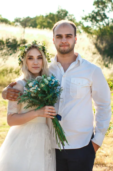 Noiva em vestido branco e coroa de flores e retrato do noivo no dia ensolarado de verão. Conceito de casamento ao ar livre rústico. Foco seletivo suave . — Fotografia de Stock