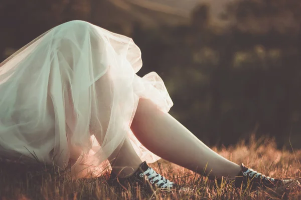 Converse ayakkabı ve günbatımı ışık açık beyaz tül etek çekici genç kadın bacaklar üzerinde yakından görünümü. — Stok fotoğraf