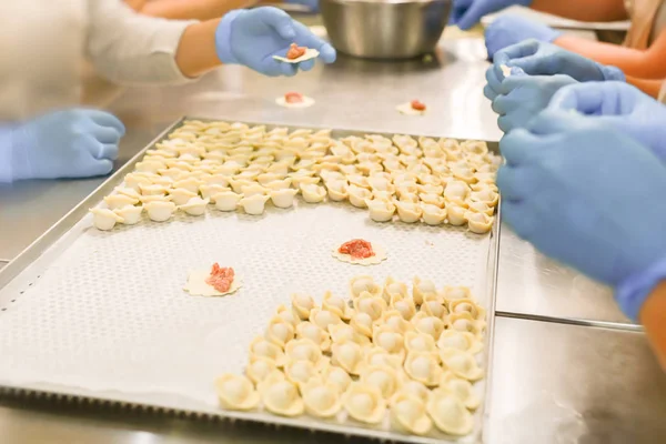 Köfte üretim süreci. Mum kağıdı ile kaplı tepsi üzerinde mavi lastik eldiven ve nemsi işverenlerin elleri.