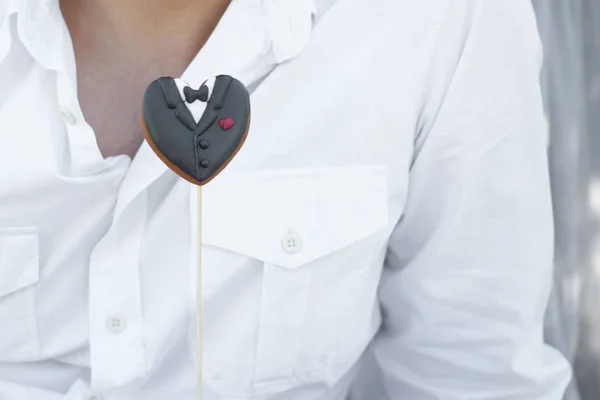 Las galletas en forma de la ropa del novio sobre los palos al hombre en el fondo blanco de la camisa — Foto de Stock