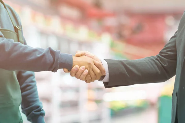 Business handshake employer and worker on blurred super market background