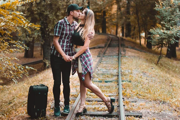 A young couple of lovers missed the train. A kiss on the rails in the autumn forest waiting for the next train. — Stock Photo, Image