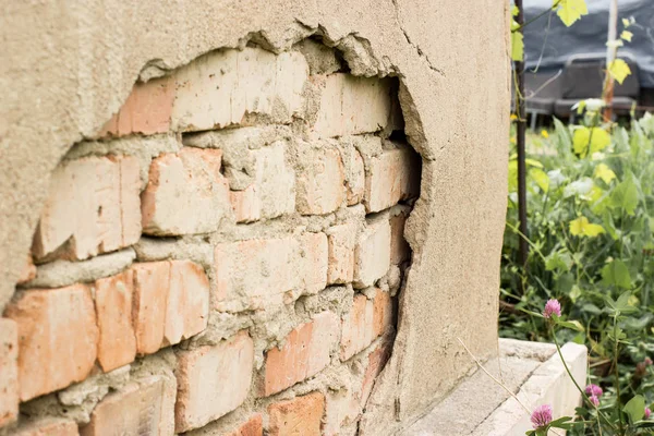 Teknoloji dışı alçı. Tuğla ile çatlamış alçı cephe duvarı.