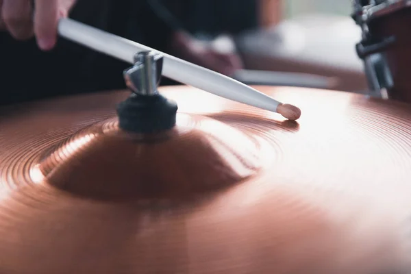 Primo piano della mano di un batterista che tiene bastoni di tamburo bianchi mentre è seduto dietro un set di tamburi . — Foto Stock