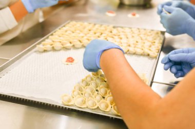 Köfte üretim süreci. Mum kağıdı ile kaplı tepsi üzerinde mavi lastik eldiven ve nemsi işverenlerin elleri.