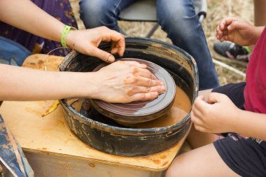 Çocuklarla çömlekçi tekerleğinde seramik üretim sürecine yakından bak. Çocuk konsepti ile Kil el sanatları.