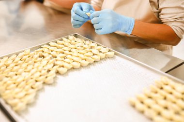 Köfte üretim süreci. Mum kağıdı ile kaplı tepsi üzerinde mavi lastik eldiven ve nemsi işverenlerin elleri.