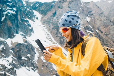 Güzel genç kadın elinde cep telefonu tutun, akıllı telefon kişi tipi mesaj, kaya kar dağ da gezi planlama turist seyahatleri dinlenmek, hipster kış doğa keyfini çıkarın