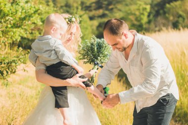 Sıcak ve güneşli yaz gününde buğday tarlasında birlikte yürüyen çocuklu mutlu bir aile. Yumuşak odaklama.