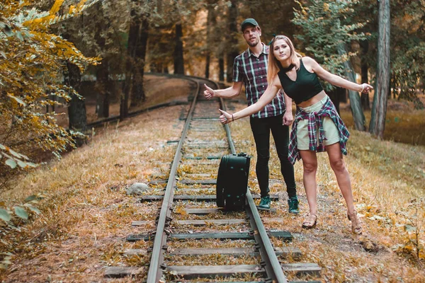 Un jeune couple d'amoureux a raté le train. Autostoppeurs sur les rails dans la forêt d'automne en attendant le prochain train . — Photo