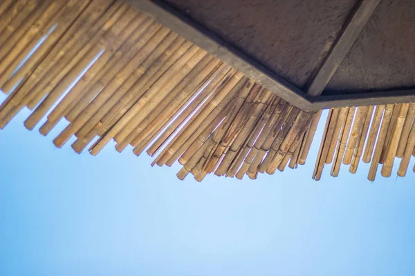 Плетеный зонтик на крыше и голубое небо. Натуральные бамбуковые зонтики и зонтики для зонтиков на синем берегу моря. Большие соломенные зонтики . — стоковое фото