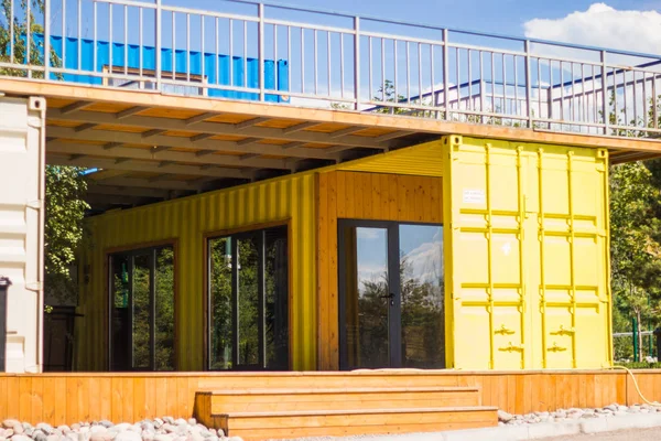 Almat, Kazakistan - 08 Temmuz 2019: Plajda sarı konteynerlerin nakliyesi ve mavi gökyüzü arka planından yapılan modern metal bina evi .