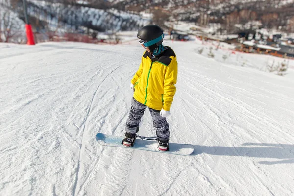身穿黑色头盔的滑雪者 黄色的夹克滑落在滑雪板上的蓝色雪板上 — 图库照片