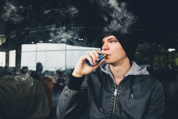 Vape buharlı şehir çocuğu açık hava kafeteryasında gelişigüzel takıl.