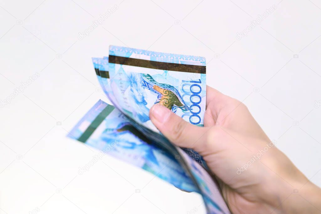 Counts banknotes of tenge national currency of Kazakhstan. White background.