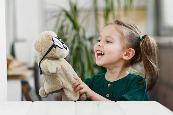 Uśmiechnięta dziewczynka z Kaukazu nosi i bawi się w niedźwiedzie kukiełki. Zostań w domu. — Zdjęcie stockowe