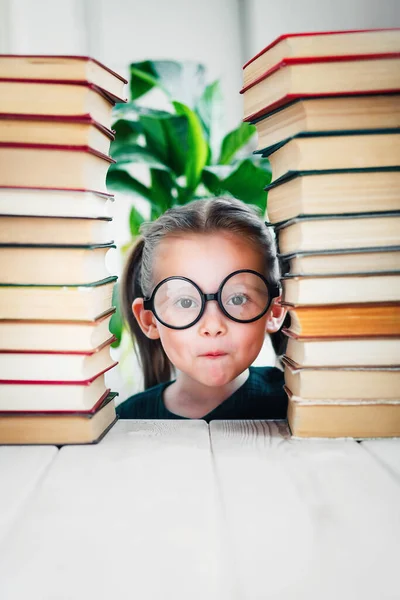 Roztomilý portrét předškolního věku dívka v kulaté tvaru brýle mezi knihami hromada s kopírovacím prostorem — Stock fotografie