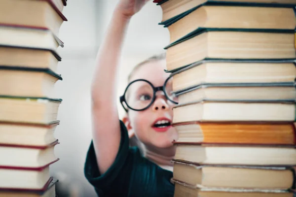 Little preschool girl genius reads a ton of books. Kids education and early development concept — Stock Photo, Image