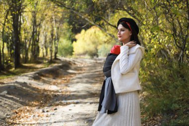 Güzel, genç bir anne ve bebeği dışarıda asılıymış. Kadın çocuğunu taşıyor ve sonbahar doğasında yürüyor. Bebek giyme konsepti