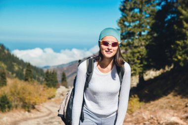 Gözlüklü genç bir kadın dağlık bir alanda yaya olarak seyahat eder..