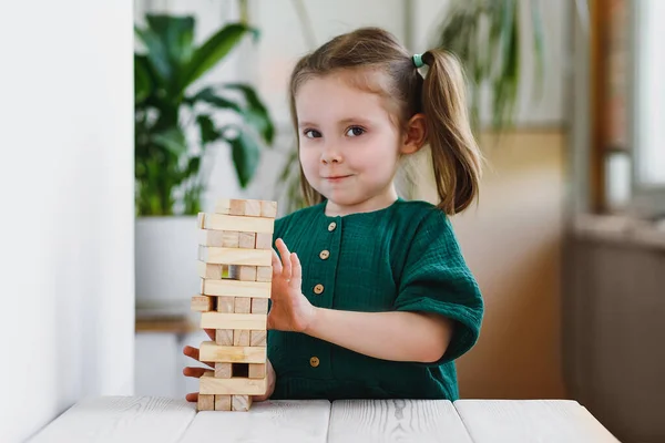Uśmiechnięty Canny Słodkie Dziecko Zielonej Sukience Dotykając Drewnianej Wieży Jenga — Zdjęcie stockowe