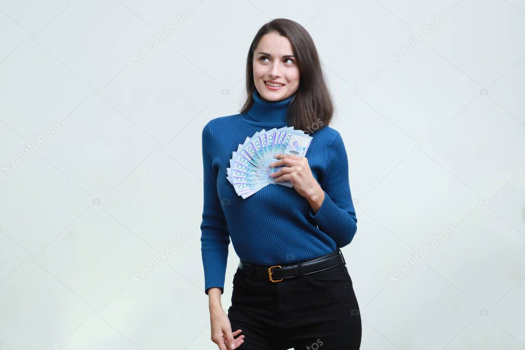 A young girl presses tenge money against her chest.