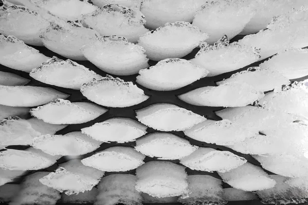 White icicles on a dark background. Ice in the dark water.