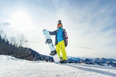 Dağlardaki snowboardcu freerider karlı dağların arka planına inmeye hazırlanıyor..