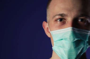 Kafasında avuç içi olan, tıbbi maske takmış, beyaz hasta bir adam.