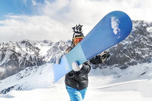 Ung kvinna i tuppkam med en snowboard framför sig — Stockfoto