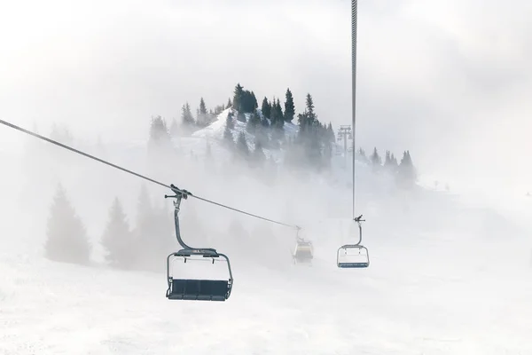 Elevador de esqui no fundo das montanhas no nevoeiro. Belo luxo melhor inverno férias fundo. — Fotografia de Stock