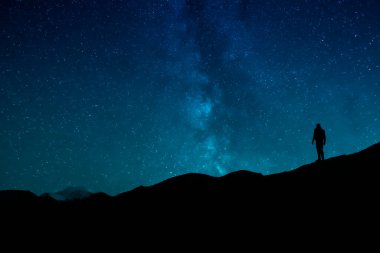 Silhouette Of Man Standing Under Starry Sky At Night Outdoors