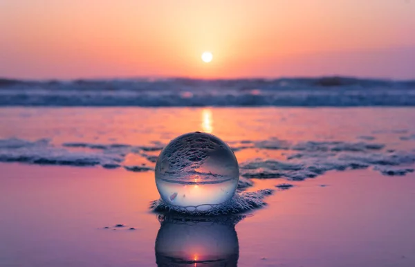 beautiful glass ball on perfect ocean seashore sandy beach at sunset sunrise