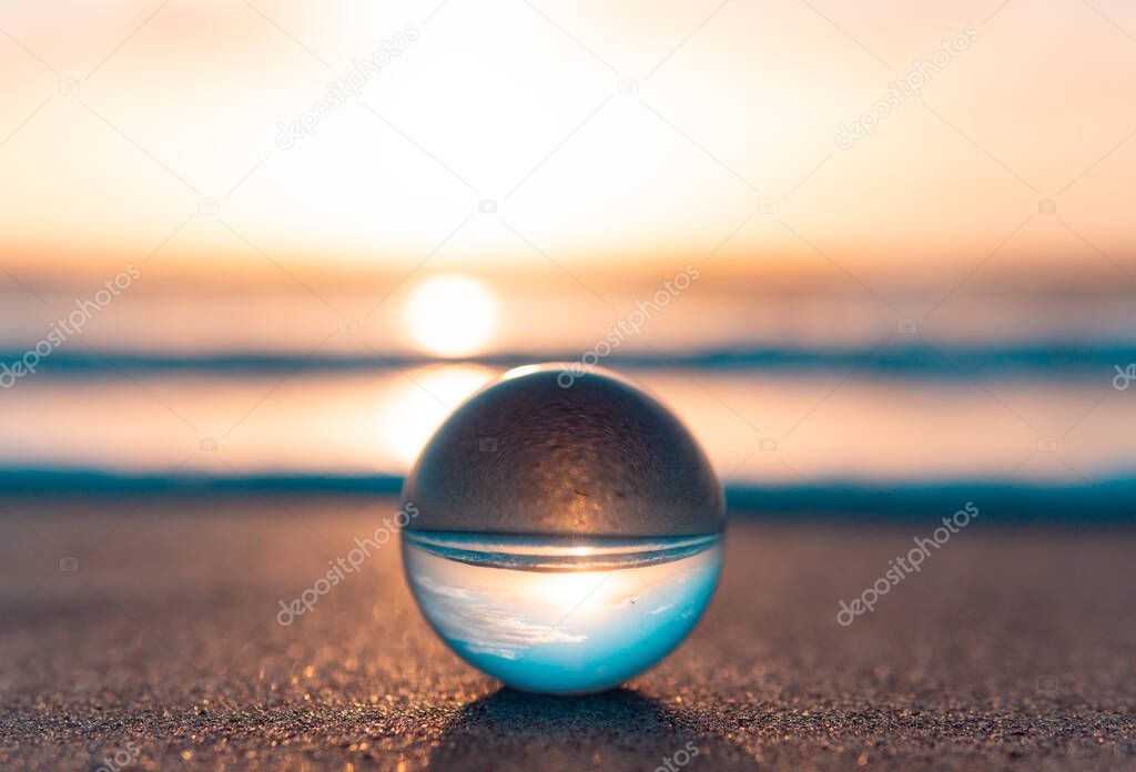 Beautiful artistic photograph of serene sunrise glass ball on sandy beach
