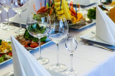 Yemekler masaya tatil için servis. Çatal bıçak takımı ve yemek restoranda beyaz masa örtüsü. Şenlikli bir ziyafet tasarlayın. Konuklar ve ziyaretçiler için lüks gıda.