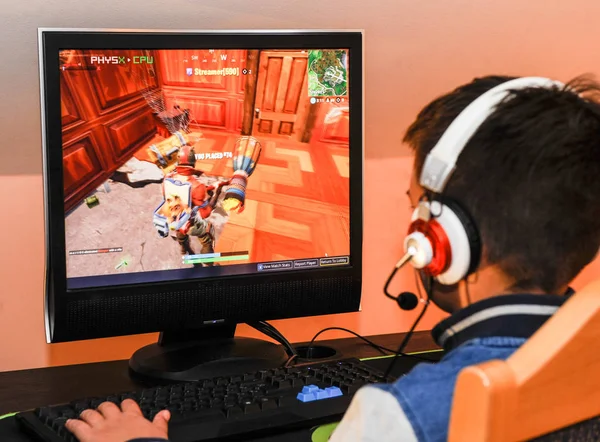 ヘッドフォンとカラフルなキーボードを身に着けているコンピューターでビデオ ゲームをプレイするゲーマー少年 ストックフォト