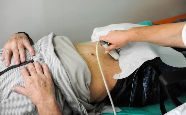医生正在使用超声波机扫描一个高级男性患者的内脏 图库照片