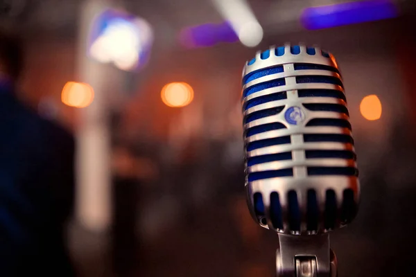 Close up of Retro microphone in concert hall with blurred lights at background