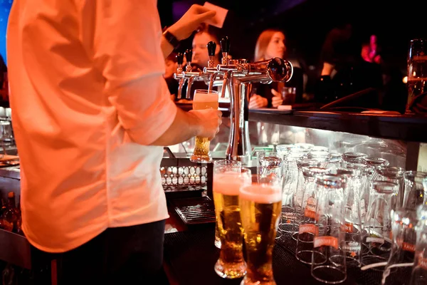 close-up of barman hand at beer tap pouring a draught lager beer