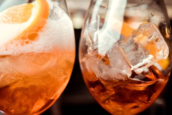 Glass with dark orange drink. Lemon peel and ice cubes. Negroni cocktail is ready. Recipe of beverage with bitter.