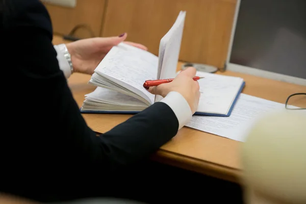 Businesswoman makes a note in notebook.