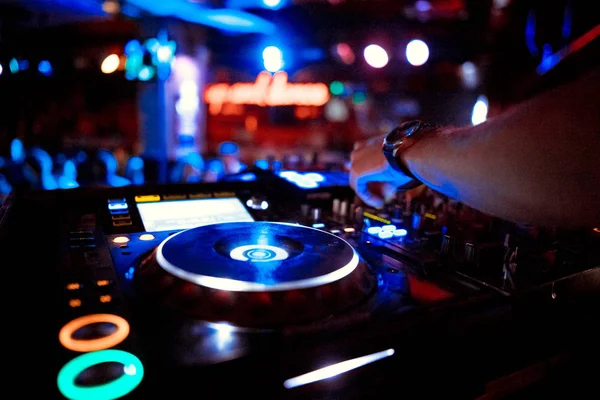 DJ mixer on the table background the night club and dancing people