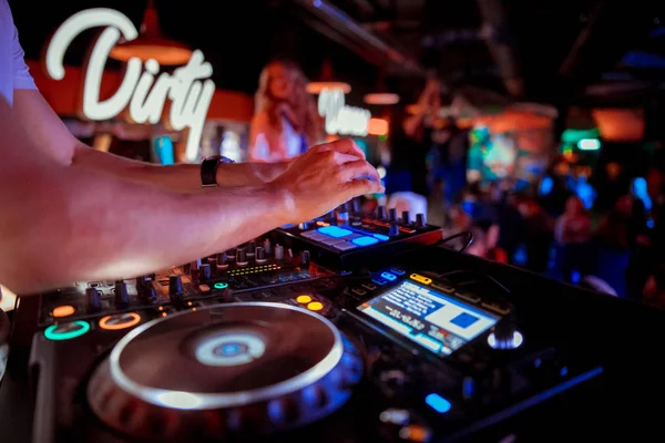 DJ mixer on the table background the night club and dancing people