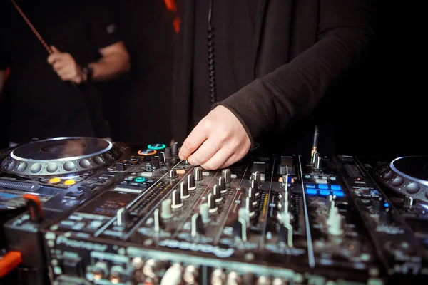 DJ turntable console mixer controlling with two hand in concert nightclub stage.