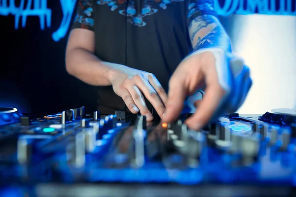 Dj mixing outdoor at beach party festival with crowd of people in background - Summer nightlife view of disco club outside - Soft focus on hand fingers - Fun ,youth,entertainment and fest concept