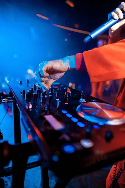 Dj mixes the track in the nightclub at party. In the background laser light show