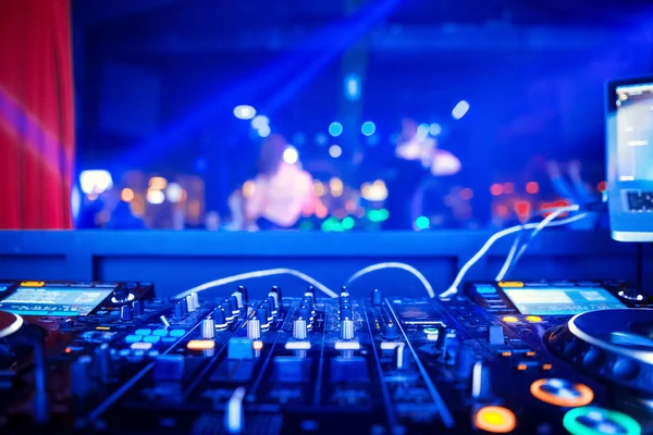 Dj mixes the track in the nightclub at party. In the background laser light show