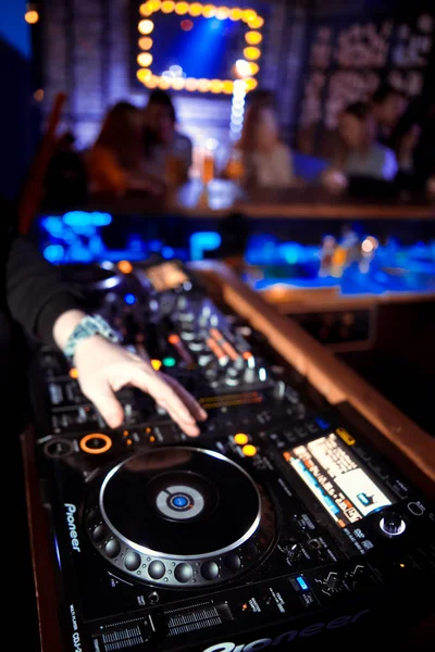 Dj mixes the track in the nightclub at party. In the background laser light show